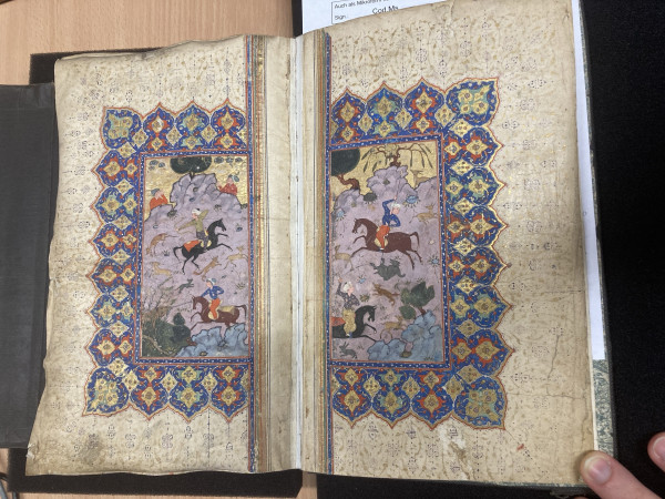Medieval Arabic manuscript, double leaves with illustration of horse riders on purple ground, with a rich gold and colour border. 