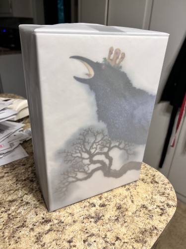 Wrapped box set of books. On the box, a black bird in a tree wears a crown.