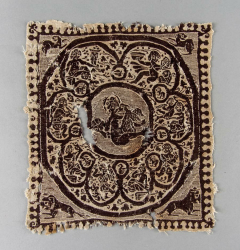 A cream and purple woven square that shows Leda and the swan in the central circle. This centre is framed by another circle with a variety of figures depicted before animals have been placed in the corners before the final square border.