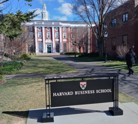 An image of Baker Library of HBS in the distance and the Harvard Business School sign in the foreground.