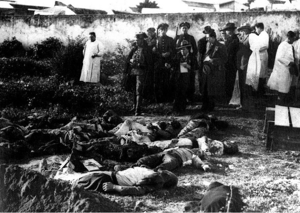 Photograph taken hours after the Casas Viejas massacre, with the bodies still lying on the ground, with priests, cops and journalists standing by. By Unknown author. Public Domain. http://www.enciclopedia.cat/enciclop%C3%A8dies/gran-enciclop%C3%A8dia-catalana/EC-GEC-0015666.xml?s.rows=100&amp;s.q=llibertari#.VKqkzMmhyVo, https://commons.wikimedia.org/w/index.php?curid=37688317