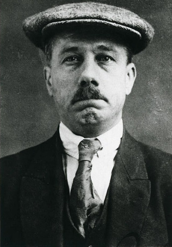 Ret Marut mug shot taken in London (1923). He is wearing a miner’s cap and sporting a narrow moustache. Marut is the most popular candidate for Traven's true identity. By British Authorities (London, 1923) - https://www.giessener-allgemeine.de/bilder/2010/03/05/12122247/529450577-39239-Pee9.jpg, Public Domain, https://commons.wikimedia.org/w/index.php?curid=92358128