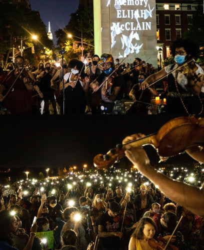 Image is two photographs.
Top photographs shows the violin vigil held on June 27, 2020 in downtown Denver.  The Colorado capital building is lit in the background, as thousands line the street individual playing their violins. In the center is a sign with illuminated white doves and lettering that reads: "In Memory of Elijah McClain".

 The bottom photo shows the arm and violin of Ashanti Floyd, as he and Lee England Jr perform while others play along.
