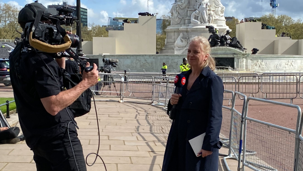 A news reporter and camera operator standing near the Mall during Coronation preparations broadcast a report over the 5G network.