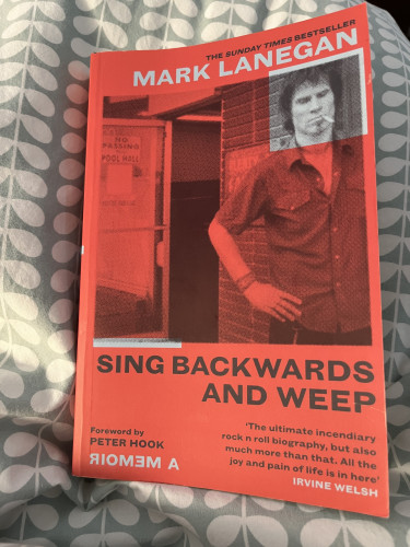 The cover of Sing Backwards and Weep by Mark Lanegan. The cover is read, with his head boxed out in black and white.