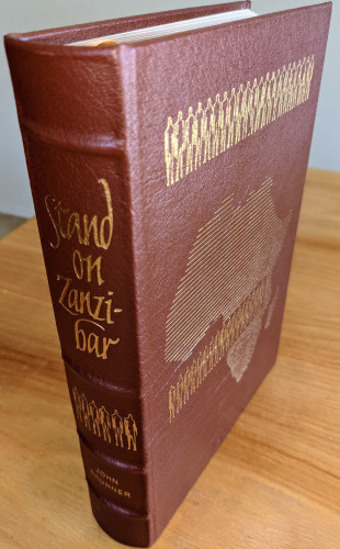 "Stand on Zanzibar" by John Brunner - Collectors Special Edition - Stunning brown colored leather volume with original artwork by Vincent DiFate - Collector's Edition Accented in 22kt gold, printed on archival paper with gilded edges, smyth sewing & concealed muslin joints - Bound In full leather with hubbed spines - Includes pristine bookplate on inside of front cover