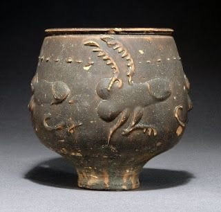 Barbotine wear vessel decorated with phallic creatures that appear to be dancing or frolicking about the body of the vessel.