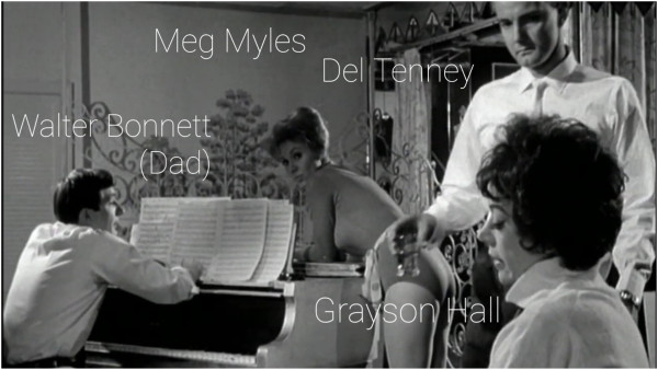 A black and white screenshot from the 1962 film, "Satan In High Heels."

The scene is a music rehearsal in a nightclub. The players, from left to right, are Walter Bonnett (Dad)–seated at the piano, Meg Myles–leaning over piano, Grayson Hall–seated, & Del Tenney–standing.