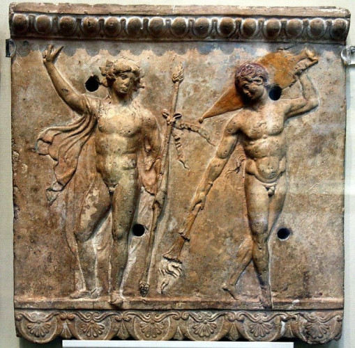 Terracotta relief of Dionysos and a satyr from his retinue. Both are in the nude, only a loose cloak floating about the god's shoulders. He has one arm raised, the other his holding his thyrsos. His satyr friend has a small tail and carries a large armphora of wine and an upside-down torch.