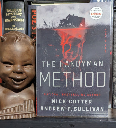 ARC paperback of THE HANDYMAN METHOD by Andrew F. Sullivan & Nick Cutter. A sinking house sits atop a ghostly red image of a house and an amorphous mess underneath the house.