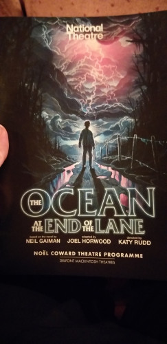 The program of the stageplay "The Ocean at the End of the Lane". It features a lone boy on a street facing a thunderous and stormy sky full of lightning