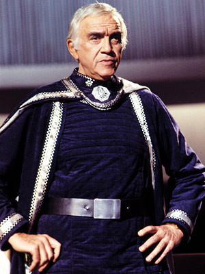Commander Adama from Battlestar Galactica. He's dressed in a dark blue uniform with silver trim, similar but not identical to that book cover.