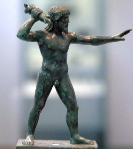 Bronze figurine of Zeus standing upright in the nude, one arm stretched out in front of him to take aim, the other holding his thunderbolt. Zeus is depicted with a beard and shoulder-length, well-kempt hair.