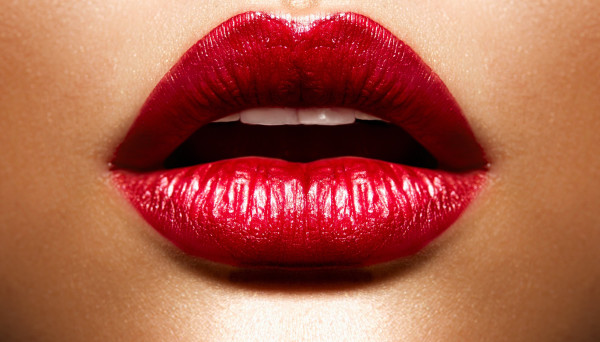 Close-up of the red-painted, slightly opened lips of a woman.